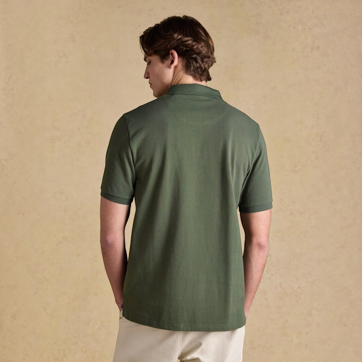 Back view of a man wearing a green BATA LTD Joules Woody cotton pique polo shirt with short sleeves.