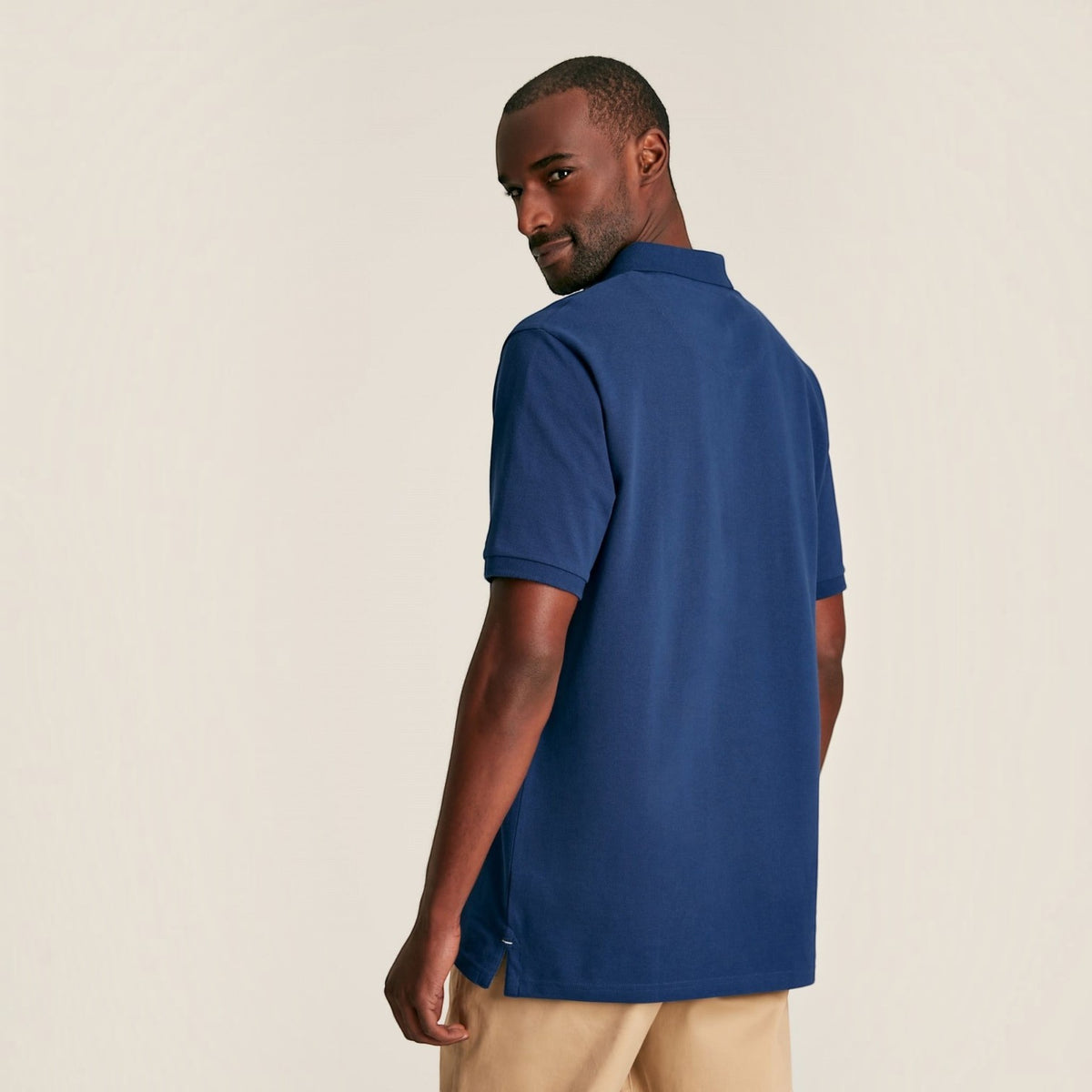BATA LTD Joules Woody blue cotton pique polo shirt worn by a man, back view showing short sleeves and side vents.