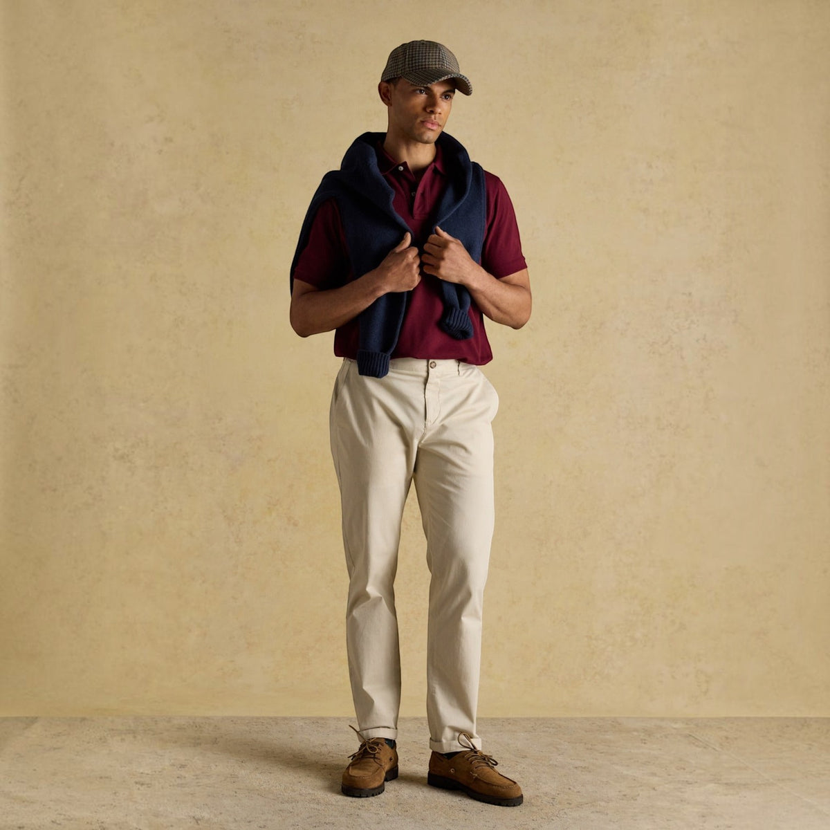 BATA LTD Joules Woody polo shirt in burgundy cotton pique with embroidered hare, worn with beige trousers and cap.