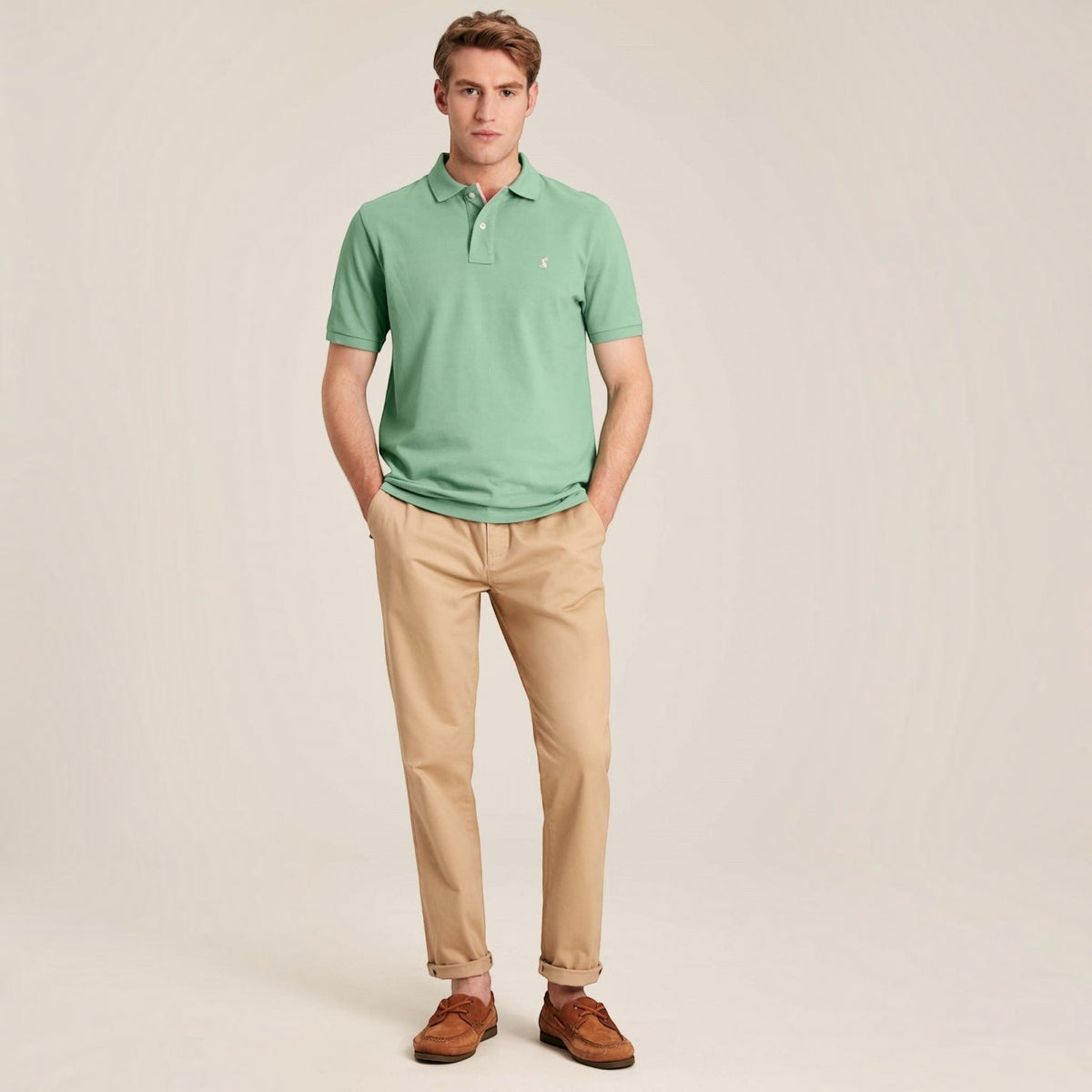 BATA LTD Joules Woody polo shirt in light green cotton pique with embroidered hare logo, worn with beige chinos.