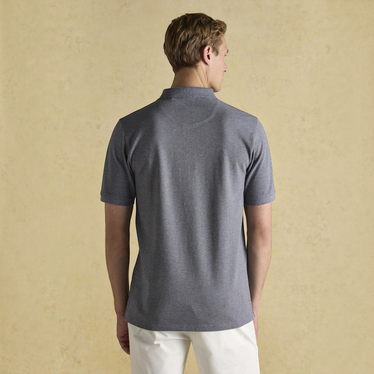 Back view of a man wearing a grey cotton pique BATA LTD Joules Woody polo shirt with short sleeves.