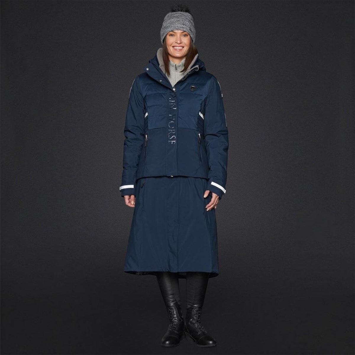 BATA LTD Mountain Horse Silver Star Hat in grey with a faux fur pompom, worn by a smiling model in a winter outfit.